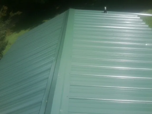 New green metal panels meeting at the ridge of a roof — Flat Roof Repair work by our crew in Peck