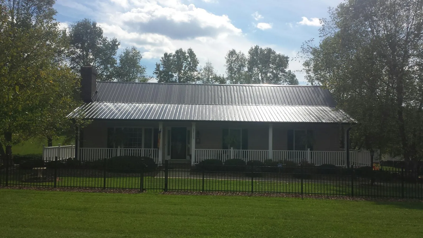 Gray metal roof on a brick ranch with a full width front porch — Gutter Guard Installation work by our crew in Peck