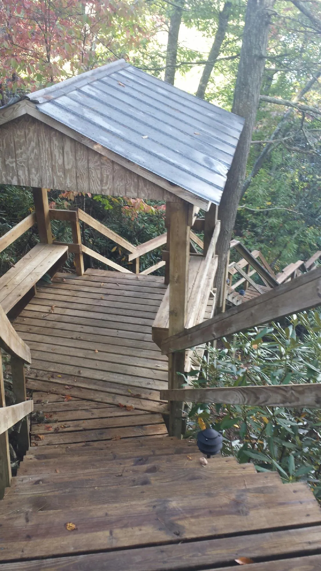 Metal roofed shelter over wooden steps on a wooded walkway — Skylight Repair & Installation work by our crew in Peck