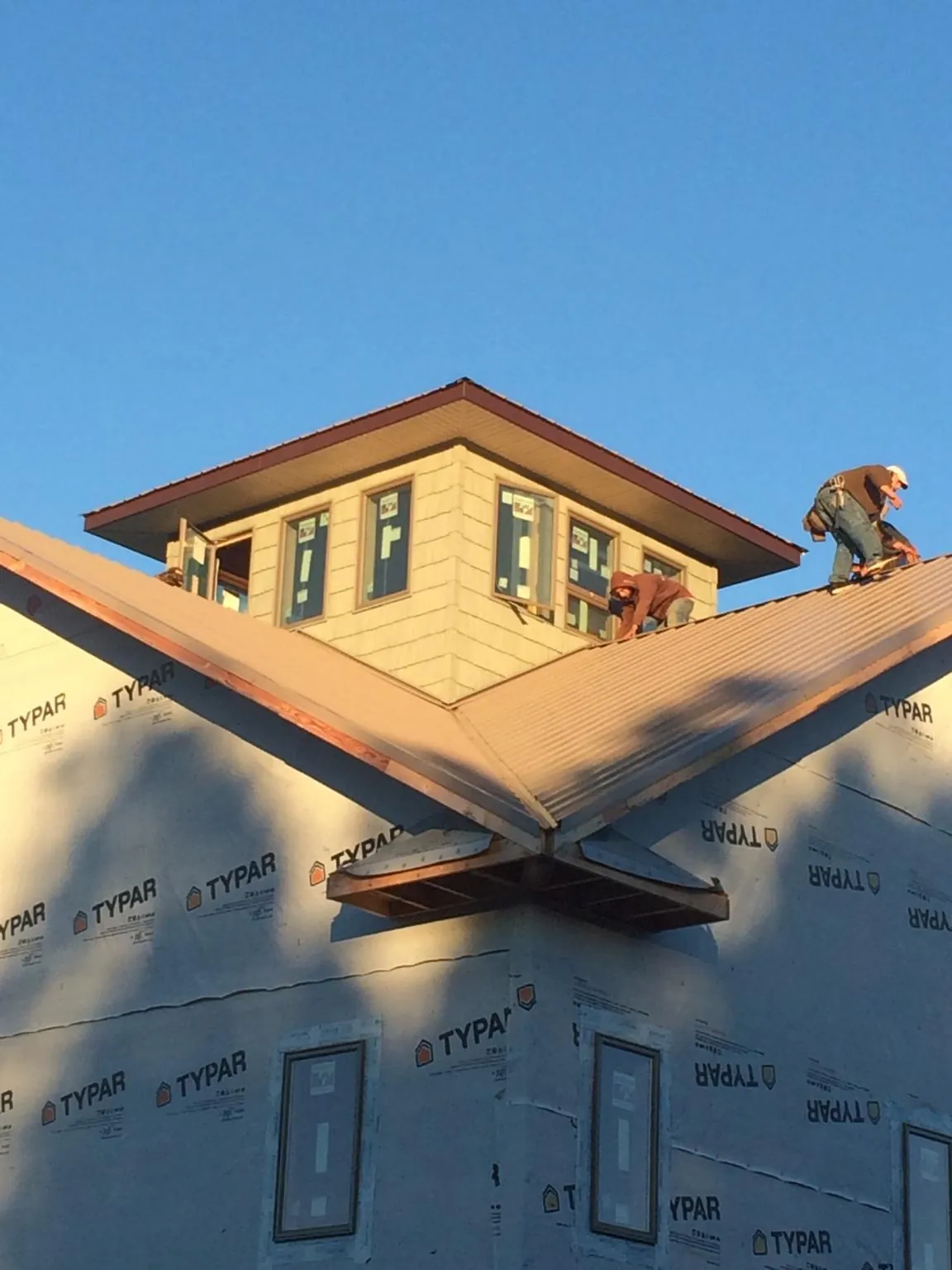 Roofers working around a rooftop cupola on a new metal roof at sunset — Roof Waterproofing in Peck by Roofing Brothers